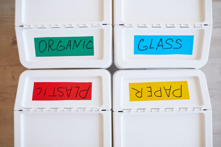 Containers for Waste Storage at Home Top view background image of four plastic bins labeled for storage and sorting waste at home, copy space