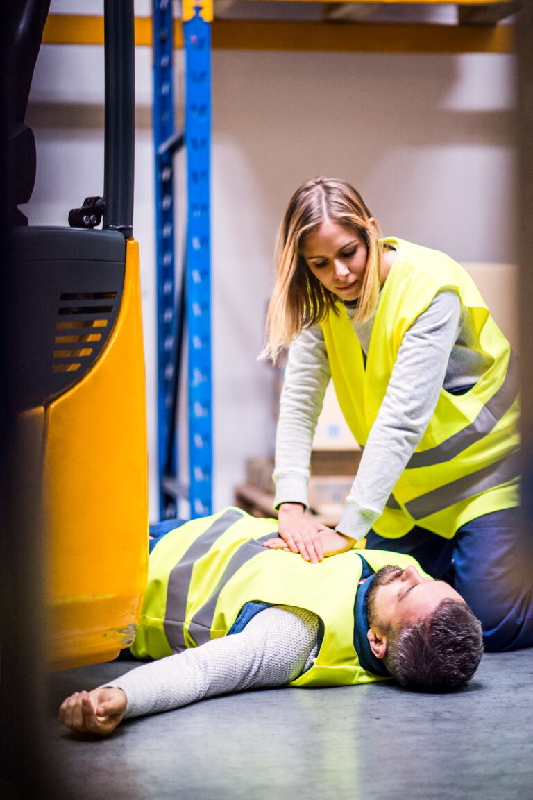 Warehouse workers after an accident in a warehouse. An accident in a warehouse. Woman performing cardiopulmonary resuscitation.
